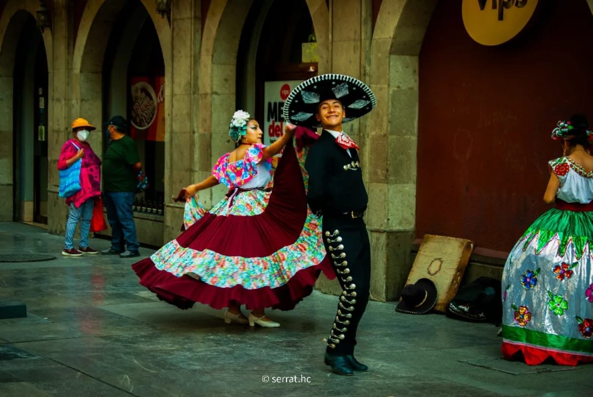 Pareja bailando folklore mexicano en el Centro Histórico, ella con falda roja en movimiento y él con traje de charro