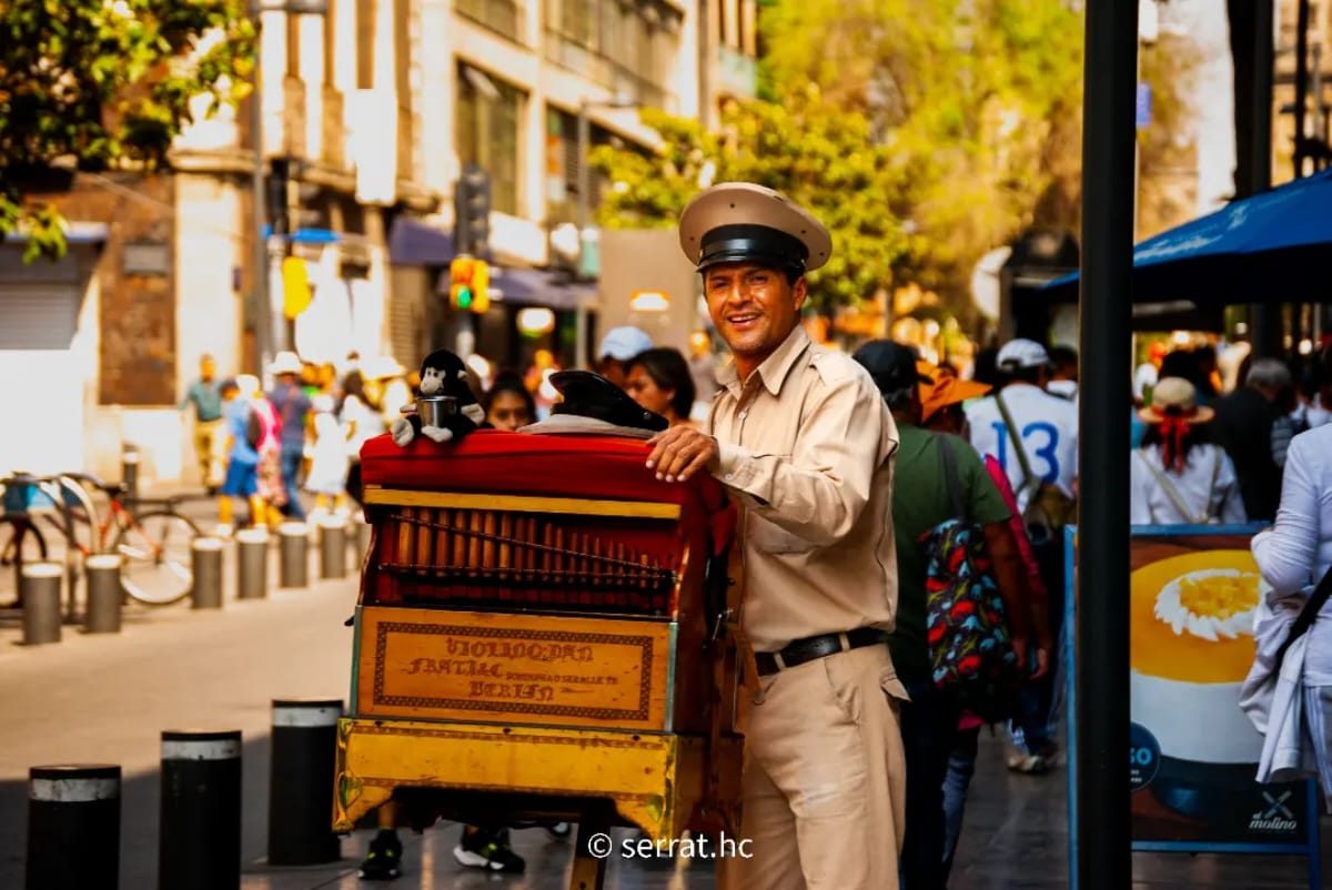 Organillero sonriendo junto a su organillo en una calle del centro de la Ciudad de México